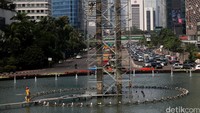 Beberapa pekerja memanjat untuk melepas tali. Ada juga yang memantau dari bawah.