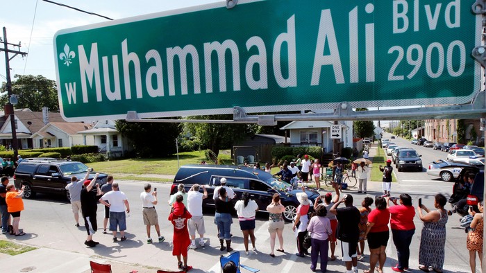 A man throws a rose over the hearse carrying the remains of Muhammad Ali during the funeral procession for the three-time heavyweight boxing champion in Louisville, Kentucky, U.S., June 10, 2016. REUTERS/Carlos Barria            FOR EDITORIAL USE ONLY. NO RESALES. NO ARCHIVES.
