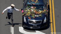 Seorang warga berlarian untuk meletakkan bunga di mobil yang membawa jenazah Muhammad Ali. Adrees Latif/Reuters/detikFoto.