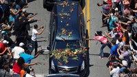 Beberapa warga asyik mengambil foto mobil jenazah. Beberapa orang lainnya melemparkan bunga ke arah mobil jenazah, bahkan hingga menutupi kaca depan mobil jenazah. Adrees Latif/Reuters/detikFoto.
