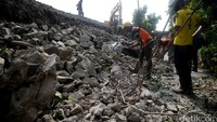 Pekerja membersihkan puing-puing beton yang menimpa mobil.