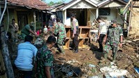 Warga membersihkan lumpur di depan rumahnya.