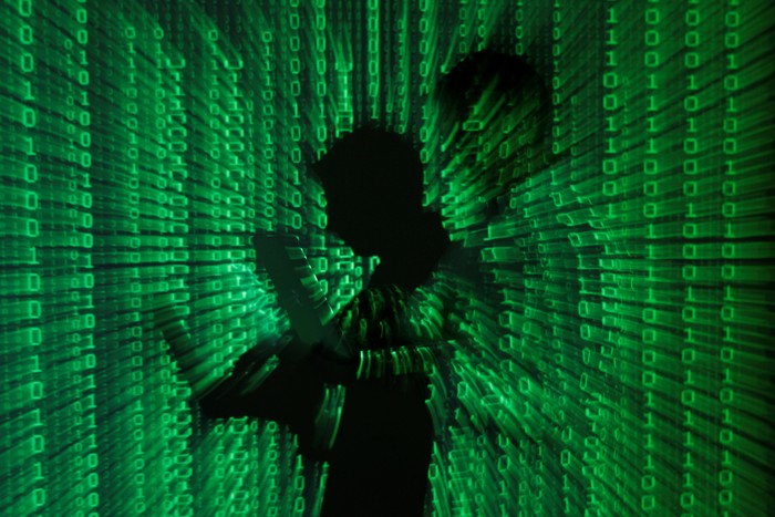 An illustration picture shows a projection of binary code on a man holding a laptop computer, in an office in Warsaw June 24, 2013. REUTERS/Kacper Pempel/Illustration/File Photo