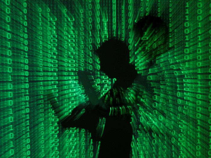 An illustration picture shows a projection of binary code on a man holding a laptop computer, in an office in Warsaw June 24, 2013. REUTERS/Kacper Pempel/Illustration/File Photo