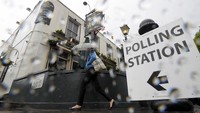 Hujan tak menyurutkan niat warga untuk memberikan hak suaranya. Toby Melville/Reuters/detikFoto.