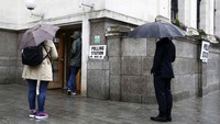 Tiga orang warga mengantre untuk memberikan hak suaranya. Neil Hall/Reuters/detikFoto.