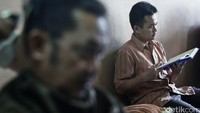 Seorang pengunjung membaca Alquran sebelum memotong rambutnya, Jumat (24/6/2016).
