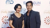 Sarah tampak mengenakan dress hitam panjang dengan motif bunga sedangkan Neil tampil dengan setelan jas hitam.
