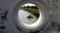 Pekerja menggunakan alat berat melakukan pengerukan dan penataan Banjir Kanal Timur di Pondok Kelapa, Jakarta Timur, Senin (27/6/2016).