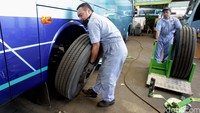 Pekerja melakukan penggantian ban bus yang akan digunakan untuk mudik lebaran.
