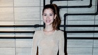 Ia tampil dibalut baju krem dipadu rok etnik dengan motif warna-warni dan heels coklat.