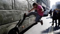 Seorang pendemo menendang sebuah mobil polisi dalam bentrokan tersebut. Ivan Alvarado/Reuters