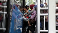 Penumpang berebut saat akan menaiki bus.