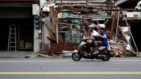 Pengendara sepeda motor melintas di depan rumah yang ambruk. Tyrone Siu/Reuters/detikFoto.