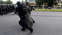 Dalam foto itu, si wanita kulit hitam yang ditangkap polisi tidak terlihat ketakutan maupun marah saat dirinya didekati dan diamankan dua polisi, yang mengenakan seragam lengkap dengan rompi antipeluru dan helm pelindung. Jonathan Bachman/Reuters/detikFoto.