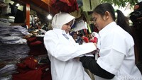 Dua orang anak menjajal seragam sekolah.
