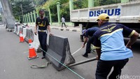 Tiga orang petugas Dishub DKI Jakarta memasang pembatas jalan.
