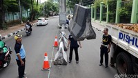 Beberapa petugas Dishub DKI Jakarta menurunkan pembatas jalan dari atas truk untuk dipasang di Jl Lapangan Tembak.