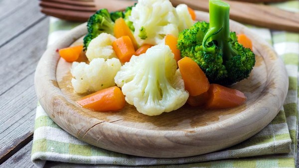 Piring sayur kukus segar berisi brokoli, wortel, dan buncis, disajikan dengan saus kacang