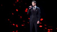 Justin tampil mengenakan setelan jas hitam dengan dasi burgundy dan sepatu coklat. Kevin Winter/Getty Images/detikFoto.