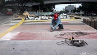 Pekerja meratakan tinggi trotoar.