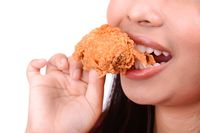 Makan fried chicken yang digoreng kecokelatan.
