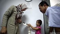Seorang anak ditimbang sebelum divaksin.