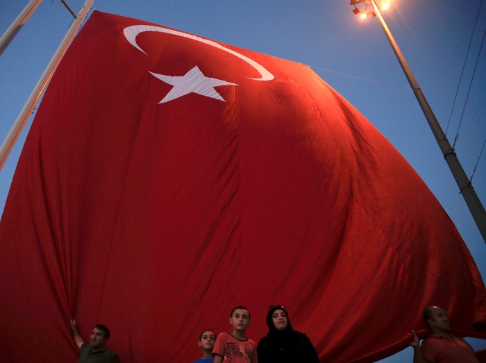 Supporters of Turkish President Recep Tayyip Erdogan stand under a giant Turkish national flag during a pro-government demonstration on Taksim Square in Istanbul, Turkey, July 17, 2016. REUTERS/Alkis Konstantinidis