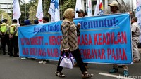 Seorang warga melintas di depan aksi buruh.