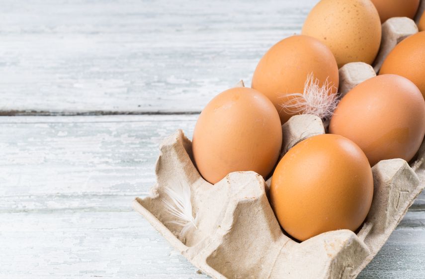 two raw egg yolks in white bowl on white background