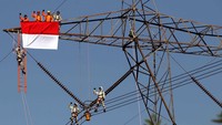 Petugas PDKB (Pekerjaan Dalam Keadaan Bertegangan) mengibarkan bendera merah putih sebelum mengganti isolator SUTET 500 KV. Ist/PLN.