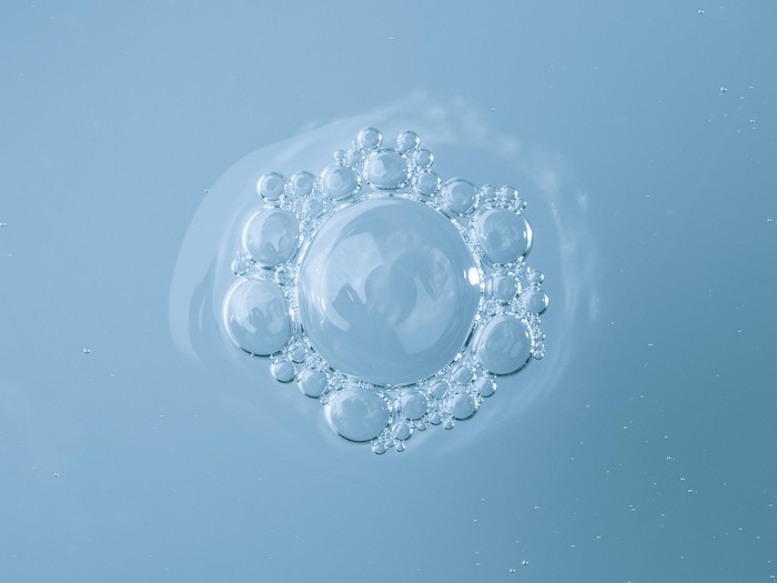 Beautiful Smiling Woman Cleansing Skin With Micellar Water And Cotton Pad While Making Daily Beauty Routine In Bathroom, Attractive Young Female Enjoying Home Skincare Treatments, Copy Space