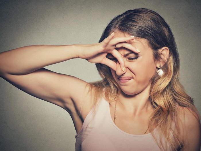 kentut Closeup portrait headshot woman pinches nose with fingers hands looks with disgust something stinks bad smell situation isolated on gray wall background. Human face expression body language reaction