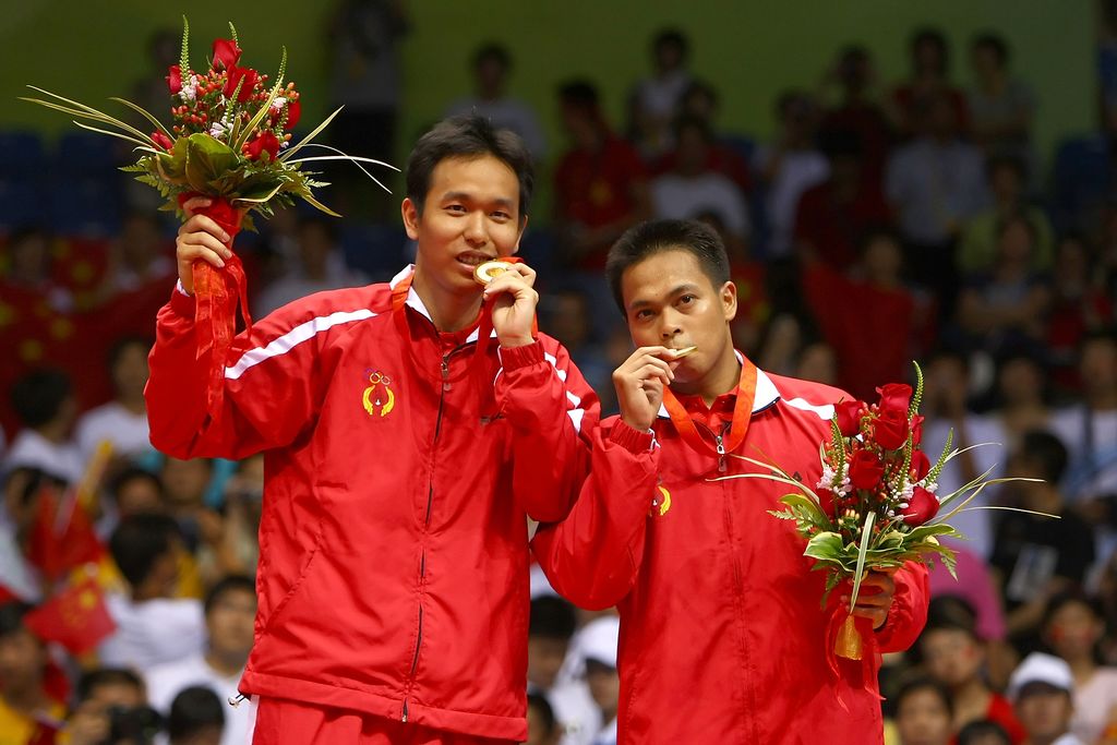BEIJING - AUGUST 16:  Hendra Setiawan (L) and Markis Kido of Indonesia bite their gold medals in the men's doubles badminton gold medal match at the Beijing University of Technology Gymnasium on Day 8 of the Beijing 2008 Olympic Games on August 16, 2008 in Beijing, China.  (Photo by Lars Baron/Getty Images)