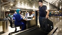 Penumpang menyerahkan bagasi ke petugas bandara.