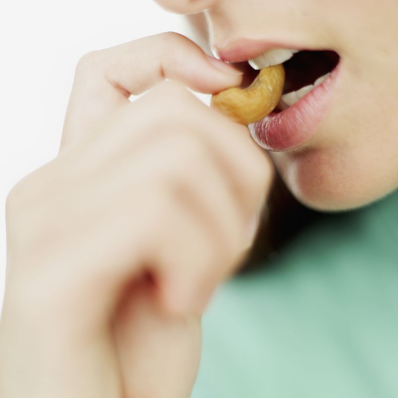 close-up of a teenage girl eating a cashew nut