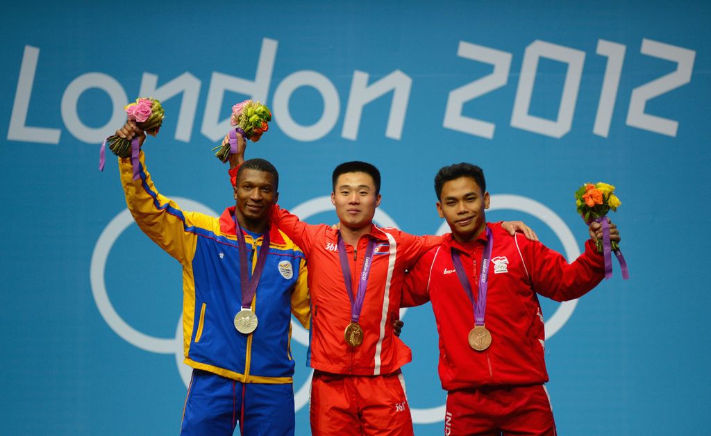 LONDON, ENGLAND - JULY 30:  Un Guk Kim (C) of DPR Korea celebrates with the gold medal, Oscar Albeiro Figueroa Mosquera (L) of Colombia with the silver medal, and Irawan Eko Yuli (R) of Indonesia with the bronze medal on the podium after the Men's 62kg Weightlifting on Day 3 of the London 2012 Olympic Games at ExCeL on July 30, 2012 in London, England.  (Photo by Lars Baron/Getty Images)