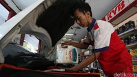 Pekerja tengah mengisi oli ke sebuah mobil di Shop&Drive di Jakarta.