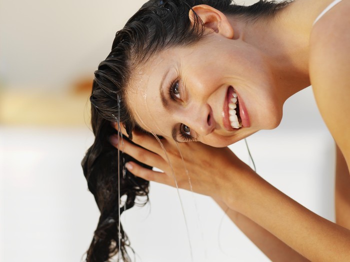 54280073 Close-up of a woman rinsing her hair
