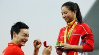 Tidak ada momen terbaik untuk melamar kekasih selain di atas podium. Itu dilakukan Qin Kai saat membuat kejutan pada kekasihnya, He Zi, dalam penyerahan medali lompat indah 3 meter (Photo by Clive Rose/Getty Images).