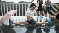 Tak puas berdiri atau duduk bersila di atas kaca, ada pula yang melakukan pose akrobatik seperti ini. Wanita ini adalah satu dari 8.000 turis yang melancong ke jembatan ini pada hari pembukaan (AFP)