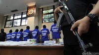 Para tersangka dihadirkan dengan penjagaan ketat polisi bersenjata api laras panjang.
