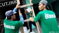 Beberapa petugas mengeluarkan barang-barang dari dalam bangunan.
