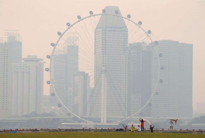 Kabut Asap di Singapura People take photos near the Singapore Flyer observatory wheel shrouded by haze August 26, 2016. REUTERS/Edgar Su
