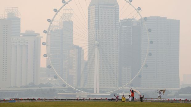 People take photos near the Singapore Flyer observatory wheel shrouded by haze August 26, 2016. REUTERS/Edgar Su
