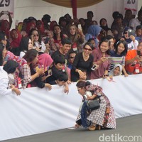 Sembari berjalan, Susi juga menyempatkan diri berinteraksi dengan penoton. Bahkan ia sempat menolong anak kecil yang kipasnya terjatuh. Secara spontan, Susi pun langsung berjongkok dan mengambilkan kipas dan mengembalikannya ke anak kecil tersebut. (Foto: Daniel Ngantung/Wolipop)