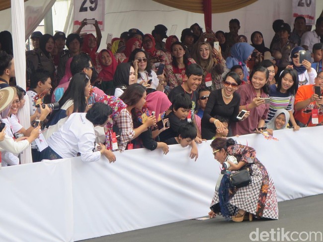 Sembari berjalan, Susi juga menyempatkan diri berinteraksi dengan penoton. Bahkan ia sempat menolong anak kecil yang kipasnya terjatuh. Secara spontan, Susi pun langsung berjongkok dan mengambilkan kipas dan mengembalikannya ke anak kecil tersebut. (Foto: Daniel Ngantung/Wolipop)