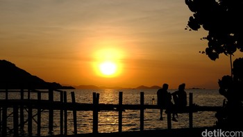 Dua orang wisatawan asing tengah menikmati matahari terbenam di sebuah dermaga di Pulau Kanawa. Foto: detikINET - Anggoro Suryo Jati