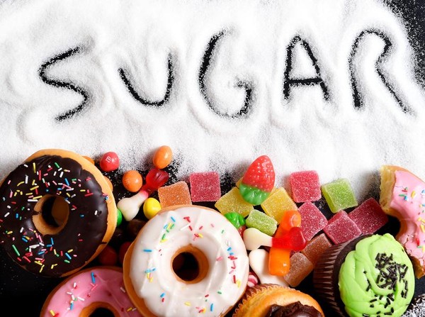 Kecanduan Gula seseorang yang tampak stres sedang memilih antara buah segar dan kue coklat, menggambarkan dilema internal yang dihadapi oleh banyak orang dengan kecanduan gula