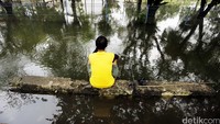 Seorang warga asyik memancing di tengah banjir.